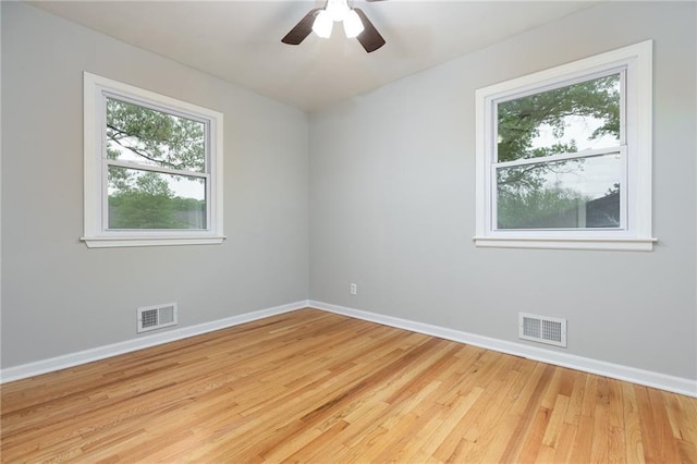 spare room with baseboards, visible vents, and wood finished floors