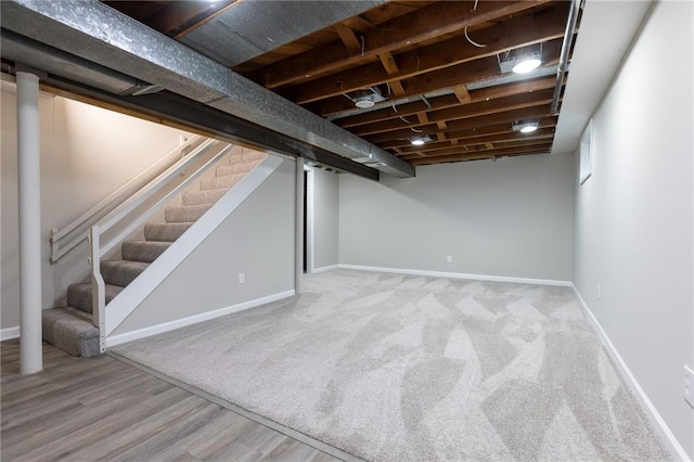 finished basement with stairway, baseboards, carpet flooring, and wood finished floors