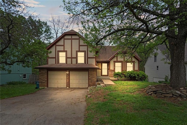 english style home with stucco siding, an attached garage, driveway, and a front yard
