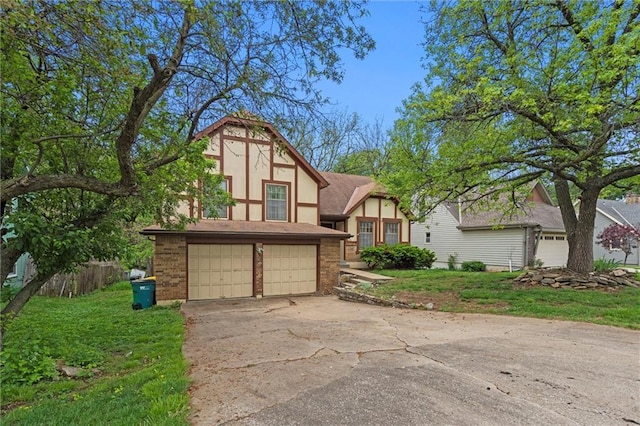 tudor home with a garage, a front lawn, stucco siding, brick siding, and concrete driveway