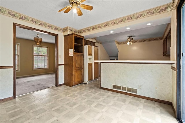 interior space with a textured ceiling, baseboards, visible vents, and ceiling fan with notable chandelier