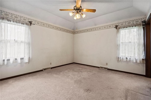 empty room featuring carpet floors, a wealth of natural light, and visible vents