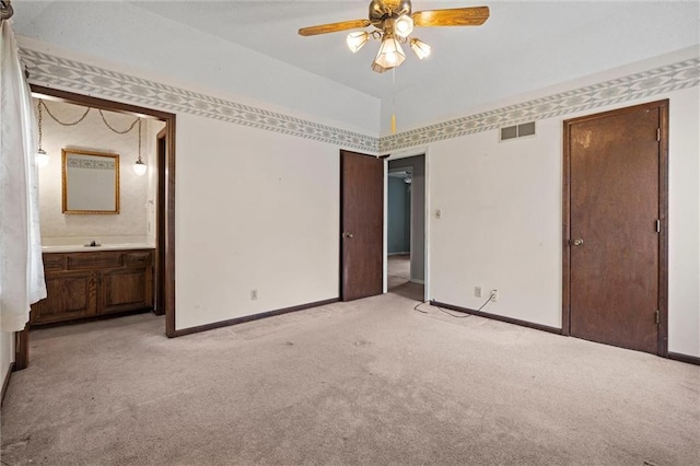 unfurnished bedroom with visible vents, baseboards, ceiling fan, light colored carpet, and connected bathroom