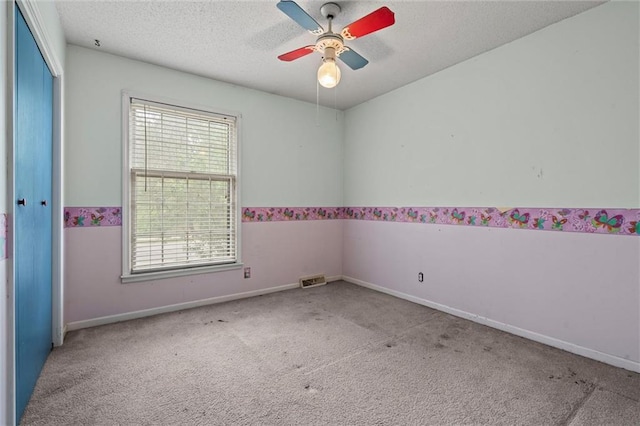 spare room featuring carpet floors, ceiling fan, baseboards, and a textured ceiling