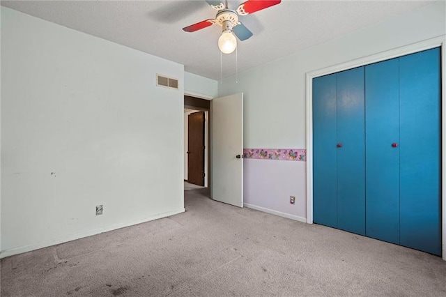 unfurnished bedroom featuring carpet flooring, a ceiling fan, baseboards, visible vents, and a closet