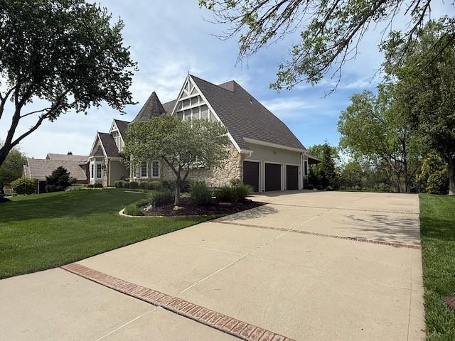 view of front of house with concrete driveway, a garage, stone siding, and a front lawn