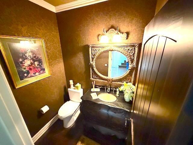 bathroom featuring crown molding, vanity, baseboards, and toilet