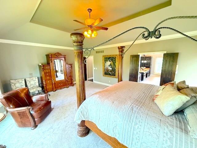 carpeted bedroom featuring crown molding, baseboards, visible vents, and a raised ceiling
