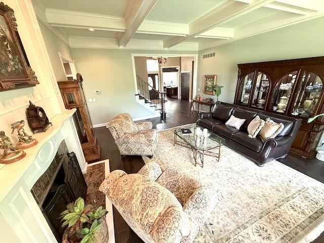 living area featuring coffered ceiling, a fireplace, dark wood-type flooring, and visible vents