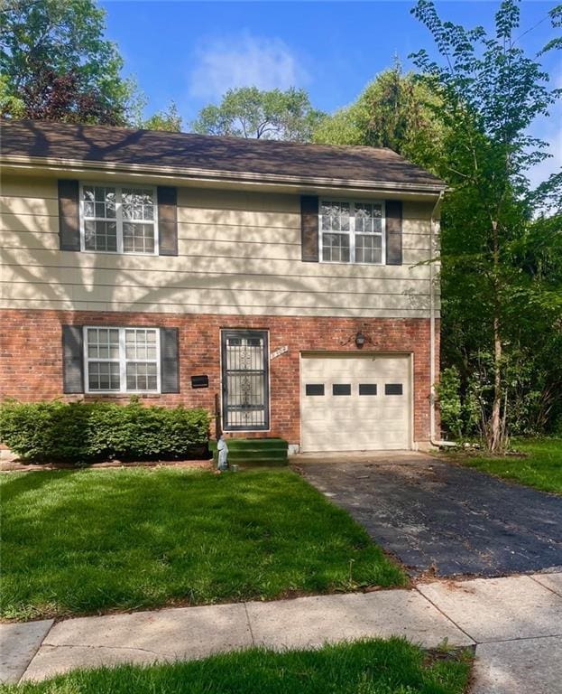 view of front of property with brick siding, aphalt driveway, a front lawn, and a garage