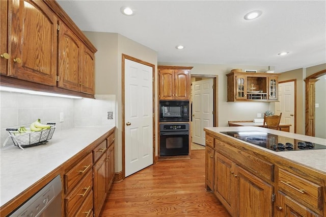 22721 E 27th Street Ct S, Blue Springs, MO 64015 - kitchen with black appliances, light wood-type flooring, light countertops, glass insert cabinets, and brown cabinets