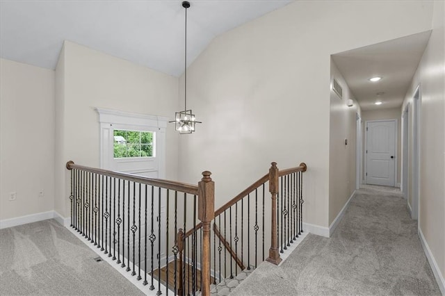 hall with carpet flooring, baseboards, an upstairs landing, and vaulted ceiling