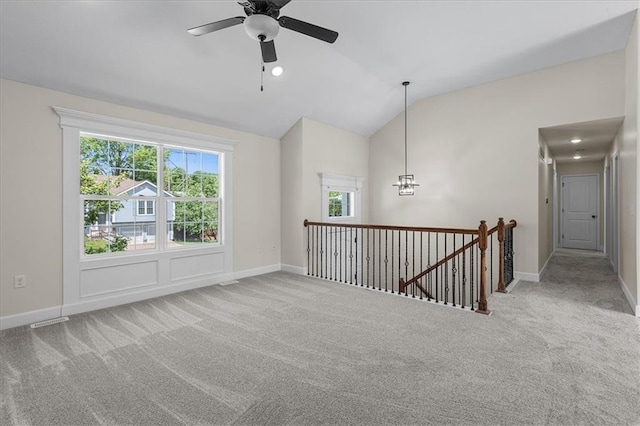carpeted empty room with baseboards, ceiling fan, vaulted ceiling, and a wealth of natural light