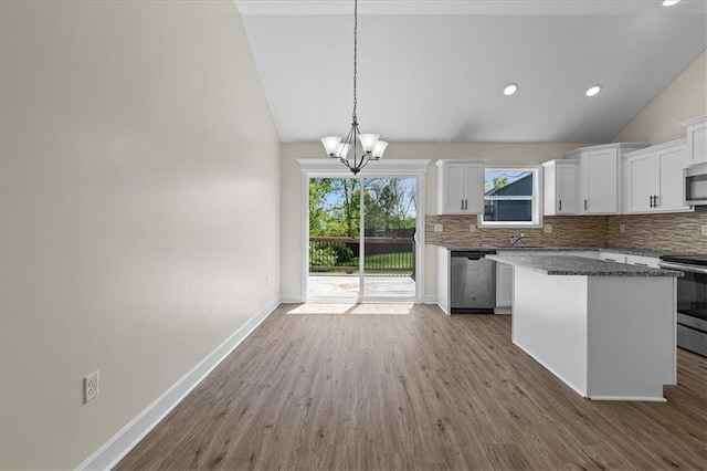 kitchen with appliances with stainless steel finishes, tasteful backsplash, white cabinetry, and a chandelier