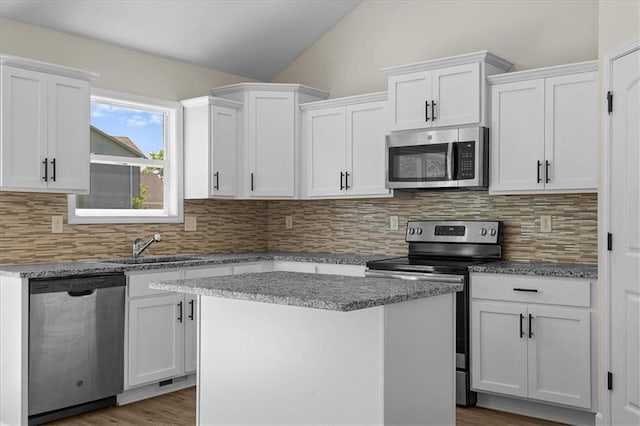 kitchen with backsplash, stainless steel appliances, white cabinetry, and lofted ceiling
