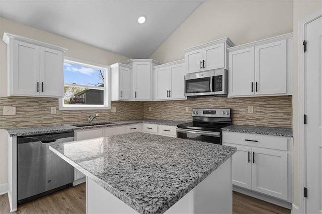 kitchen with a sink, lofted ceiling, white cabinets, and stainless steel appliances