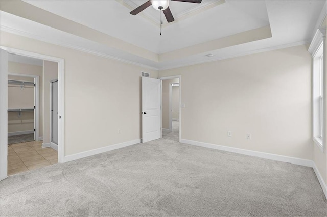 unfurnished bedroom with carpet flooring, baseboards, ornamental molding, and a raised ceiling