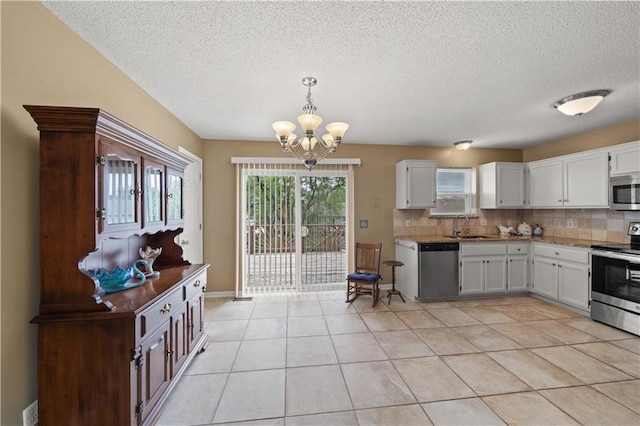 kitchen with an inviting chandelier, a textured ceiling, stainless steel appliances, white cabinetry, and decorative backsplash