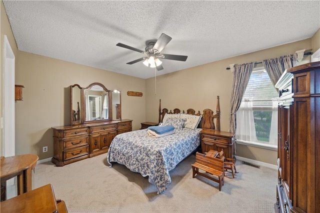 carpeted bedroom with visible vents, a textured ceiling, baseboards, and a ceiling fan