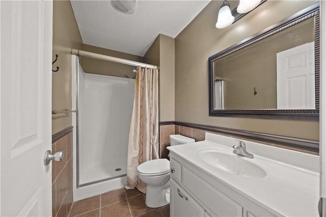 bathroom featuring vanity, a textured ceiling, wainscoting, and a shower stall
