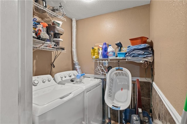 clothes washing area featuring a textured ceiling, laundry area, a textured wall, and washer and clothes dryer