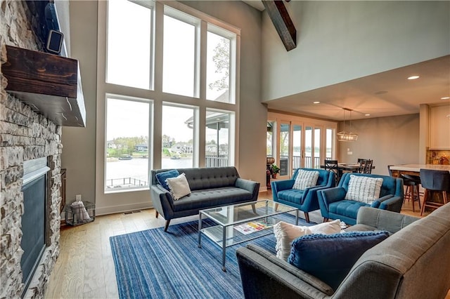 18 Black Hawk Dr, Lake Winnebago, MO 64034 - living room featuring a towering ceiling, a stone fireplace, light wood-style floors, a water view, and recessed lighting