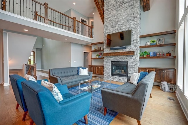 18 Black Hawk Dr, Lake Winnebago, MO 64034 - living room featuring a towering ceiling, wood finished floors, baseboards, a stone fireplace, and healthy amount of natural light