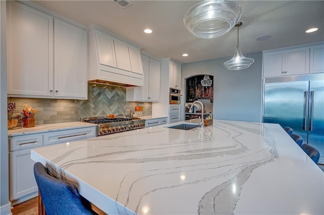 18 Black Hawk Dr, Lake Winnebago, MO 64034 - kitchen featuring appliances with stainless steel finishes, a sink, a large island with sink, backsplash, and hanging light fixtures