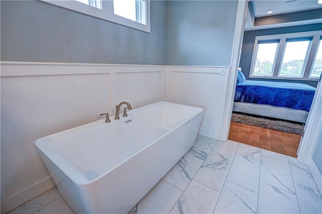 18 Black Hawk Dr, Lake Winnebago, MO 64034 - full bath with marble look tile flooring, ensuite bathroom, a soaking tub, a wainscoted wall, and a decorative wall
