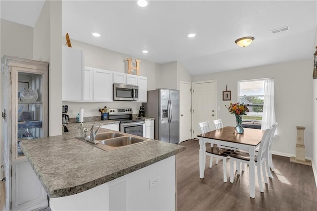 kitchen with visible vents, wood finished floors, white cabinets, a sink, and stainless steel appliances