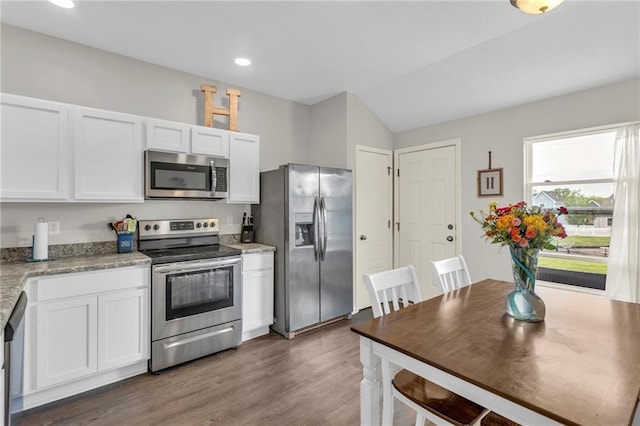 kitchen with dark wood finished floors, white cabinetry, vaulted ceiling, and stainless steel appliances