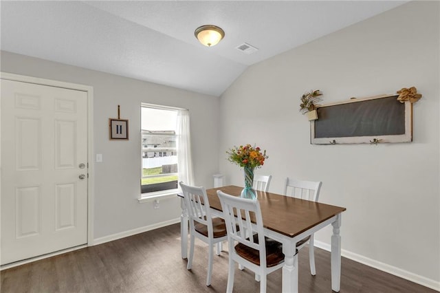 dining space with baseboards, vaulted ceiling, wood finished floors, and visible vents
