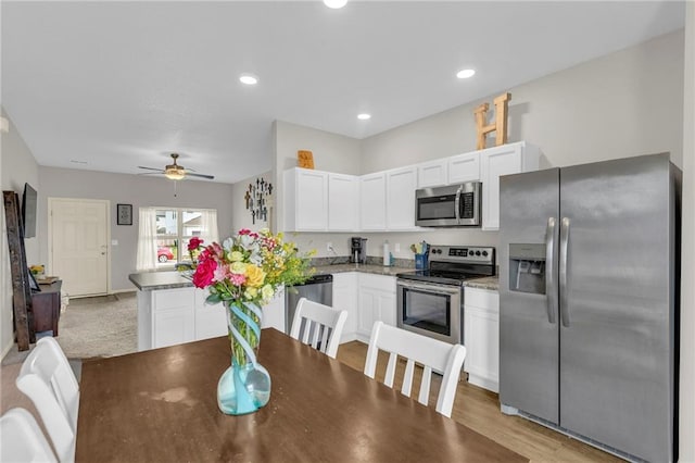 kitchen with a peninsula, ceiling fan, appliances with stainless steel finishes, and white cabinetry