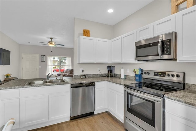 kitchen featuring a sink, appliances with stainless steel finishes, a peninsula, and white cabinetry