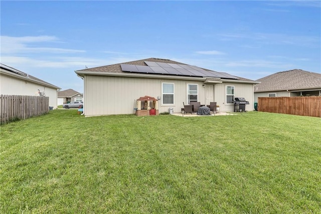 back of house with a lawn, fence, and solar panels