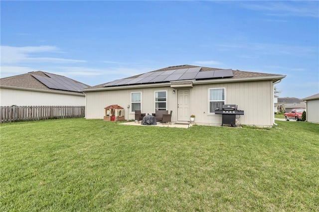 rear view of house with fence, a patio, a yard, and solar panels