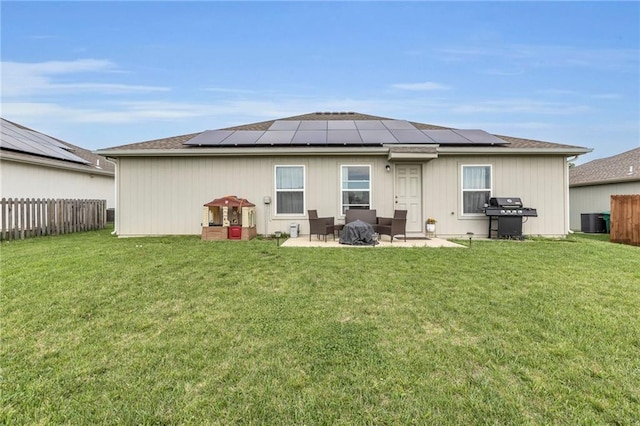 back of house with central AC unit, a patio area, a yard, and solar panels