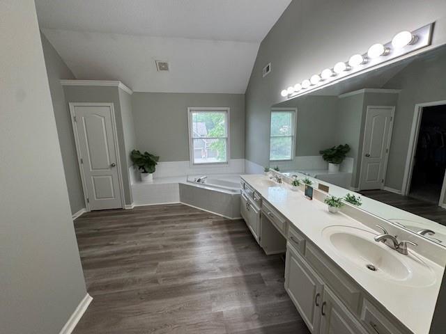 4200 Grand Ave, Leavenworth, KS 66048 - full bathroom featuring double vanity, a garden tub, vaulted ceiling, wood finished floors, and baseboards