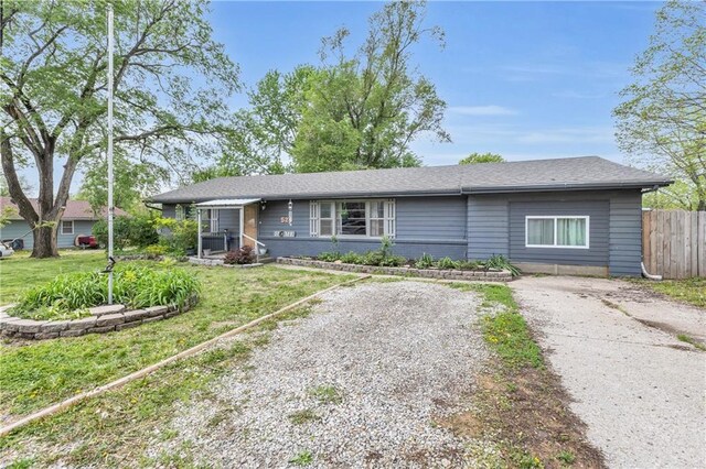 ranch-style house with fence, gravel driveway, and a front yard