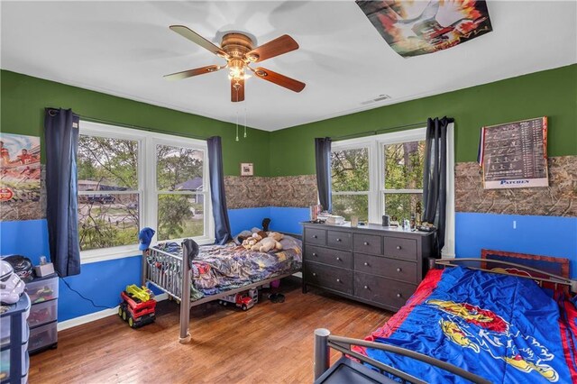 bedroom featuring multiple windows, a ceiling fan, wood finished floors, and visible vents