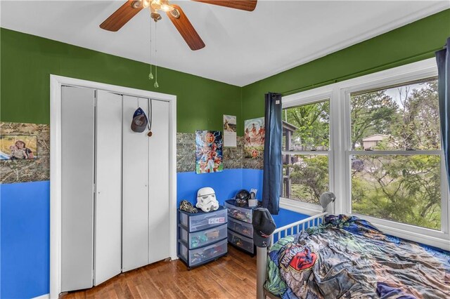 bedroom with a ceiling fan, wood finished floors, and a closet