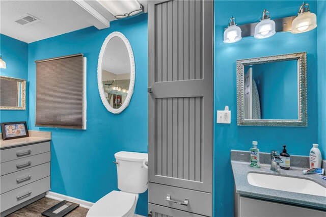 full bath featuring vanity, baseboards, toilet, and visible vents