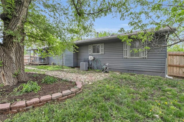 view of side of property featuring a lawn, central AC unit, and fence