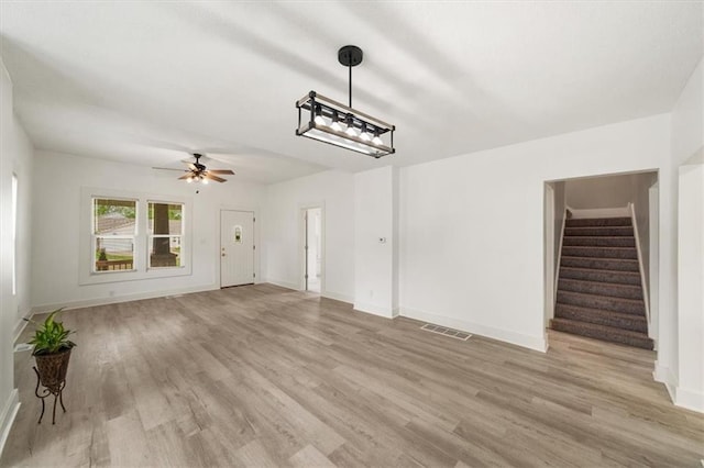 507 N Pearl St, Paola, KS 66071 - unfurnished living room featuring light wood-style floors, a ceiling fan, baseboards, visible vents, and stairway