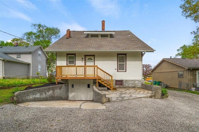 507 N Pearl St, Paola, KS 66071 - back of property featuring roof with shingles, covered porch, a chimney, and stairway