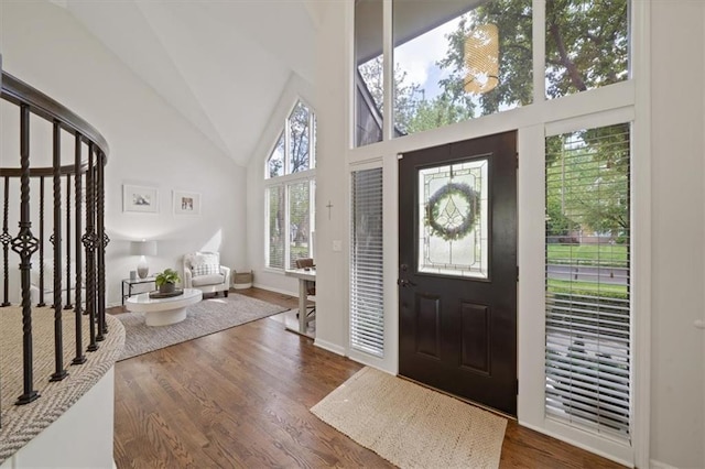 entryway featuring dark wood-type flooring, baseboards, high vaulted ceiling, and stairway