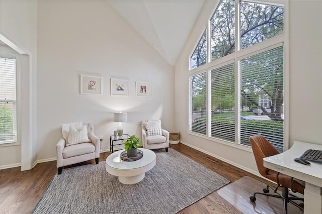 living area with baseboards, vaulted ceiling, and wood finished floors