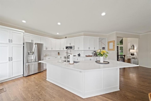 kitchen featuring light countertops, appliances with stainless steel finishes, white cabinets, and a kitchen island with sink