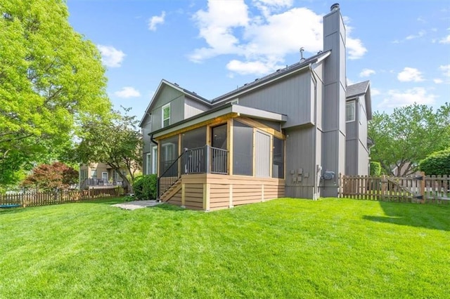 back of house featuring a lawn, fence, a chimney, and a sunroom