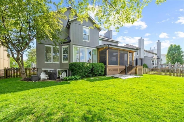back of property featuring a fenced backyard, a yard, and a sunroom